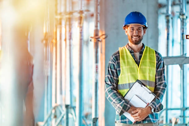 Portrait of a confident young man working a construction site Confident construction worker standing at site electrician smiling stock pictures, royalty-free photos & images