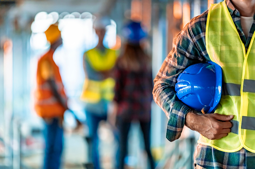 Close up of a construction worker's hand holding working blue helmet.