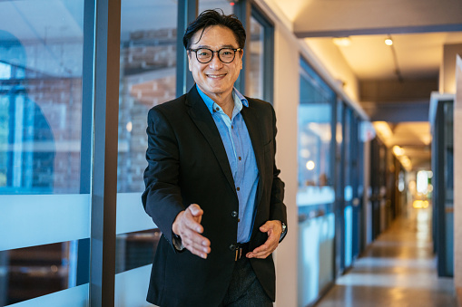 An Asian businessman reaching out his hand for a handshake.  Return to work concept.