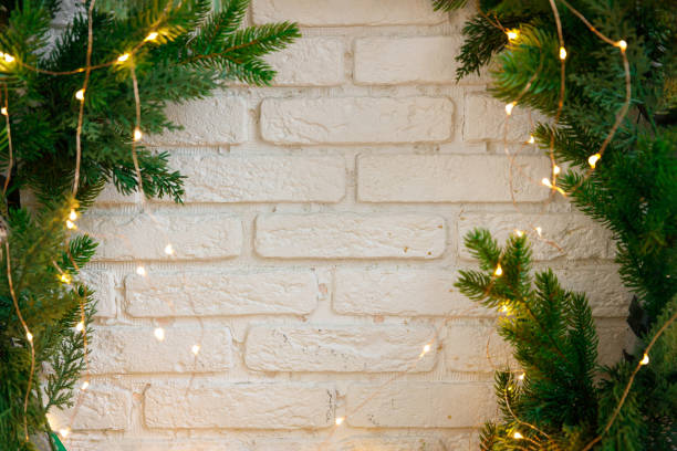 Christmas fir branches decorated with garland on brick wall