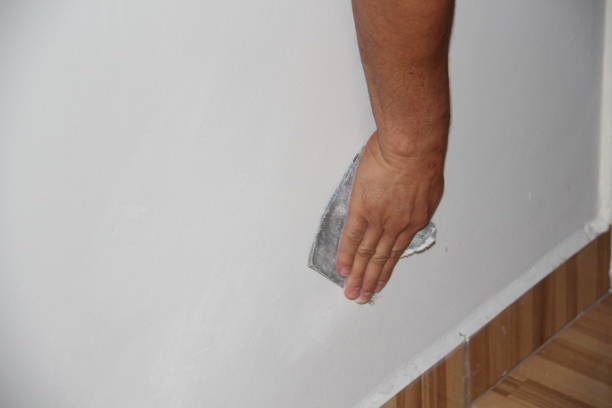 istock Close-up on a male hand sanding a white wall. 1347255530