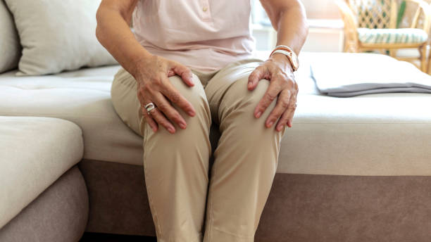 dojrzała kobieta masująca swoje bolesne kolano. - arthritis senior adult rheumatoid arthritis sadness zdjęcia i obrazy z banku zdjęć