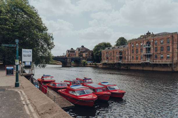 Self-drive red hire boat moored on a River Ouse in York, UK. York, UK - June 22, 2021: Self-drive red hire boat moored on a River Ouse in York. Hire boats are a popular activity to explore the city founded by the ancient Romans. ouse river photos stock pictures, royalty-free photos & images