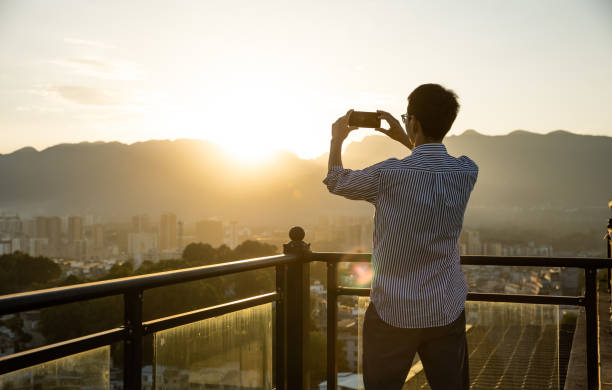 istock Man taking pictures of sunset from rooftop 1347258869