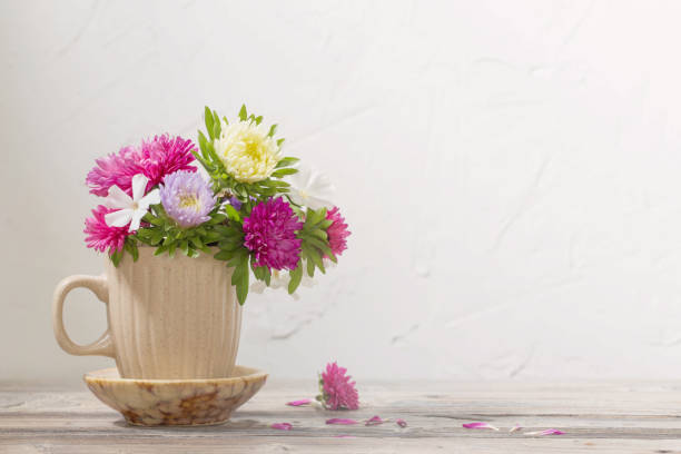istock beautiful flowers in cup on wooden table on background white wall 1347260670