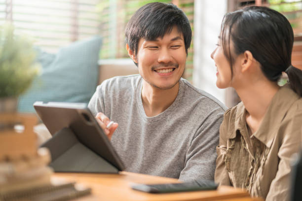 istock home isolate quarantine,asian and lover marry couple sit relax using laptop and tablet working from home or shopping online surfing social media with cheerful in living room home interior background 1347262189