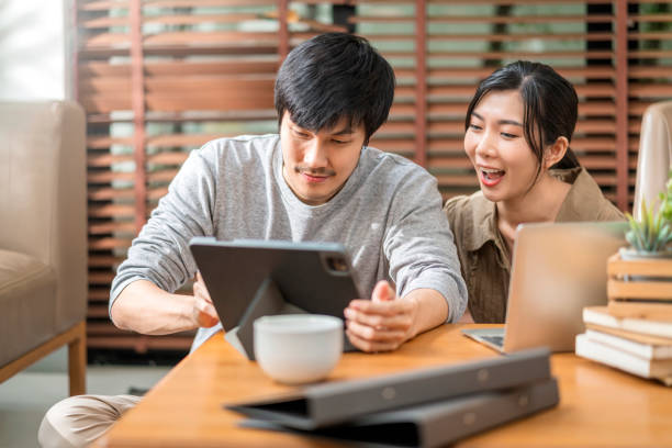 istock home isolate quarantine,asian and lover marry couple sit relax using laptop and tablet working from home or shopping online surfing social media with cheerful in living room home interior background 1347262192