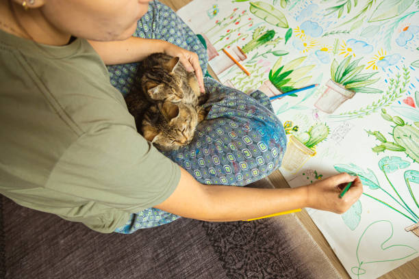 istock While her cat and kitten sitting in her lap, dedicated female artist drawing 1347263185