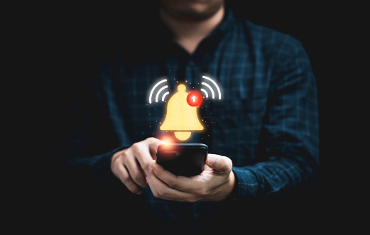 Hombre de negocios sosteniendo un teléfono inteligente con timbre amarillo virtual sonando para el concepto de alerta de notificación de la aplicación. photo