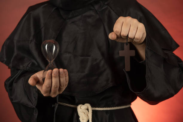 istock A man in a monastic cassock holds an hourglass and a crucifix in his hands 1347264547