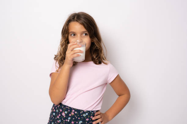 istock Smiling little girl drinking milk isolated over white background. 1347264903