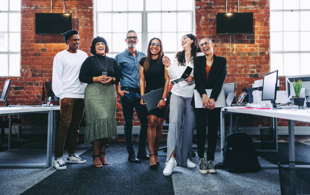 istock Group of businesspeople laughing in a modern office 1347265626
