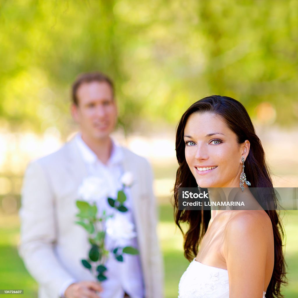 couple juste marié avec homme tenant des fleurs - Photo de 30-34 ans libre de droits