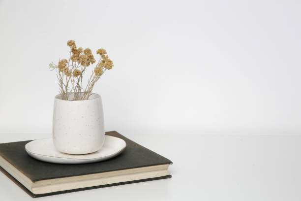 istock Ceramic mug with dry Everlasting flowers on books with on the table. Simple home decor. 1347267780