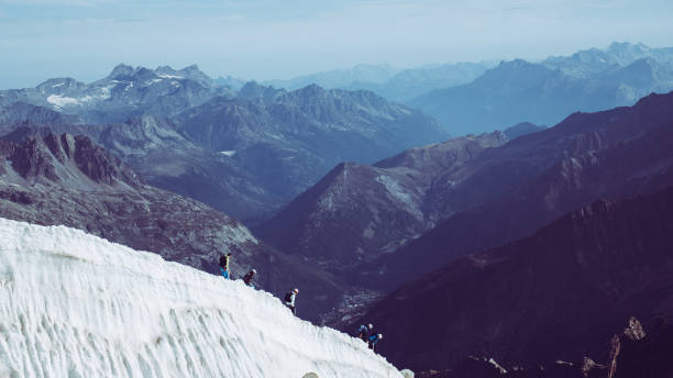 Mountain climbing team moving up in a row in high altitude mountain peak. Winter landscape with deep snow