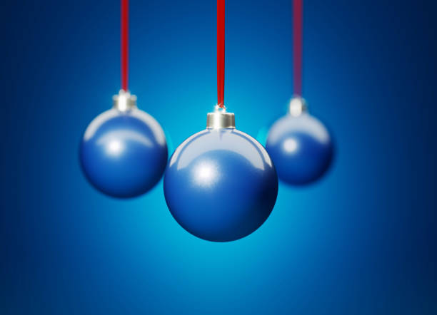 Three blue Christmas baubles hanging over blue background. Christmas and festivity concept. Horizontal composition with selective focus and copy space.