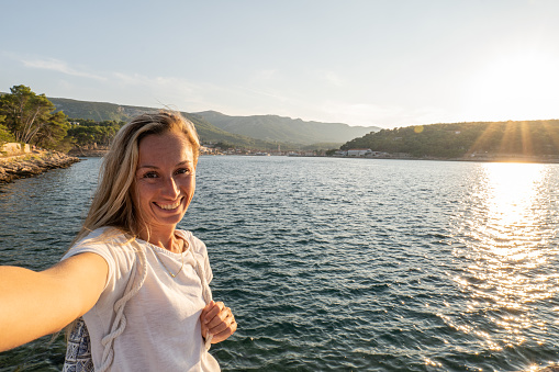 Traveler woman enjoying the sea lifestyle, Croatia\nShe captures a selfie photo on a dock