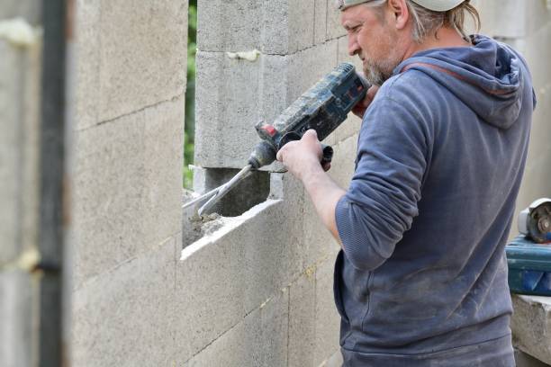 istock Worker building a wall on a house and drilling into a wall with manual drill 1347279126