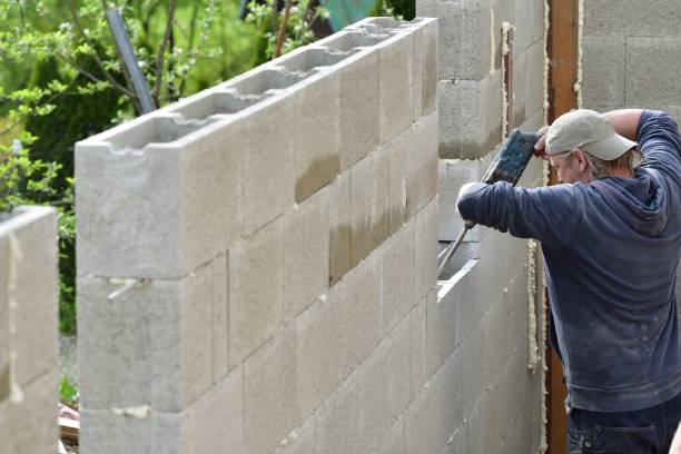 istock Worker building a wall on a house and drilling into a wall with manual drill 1347279153
