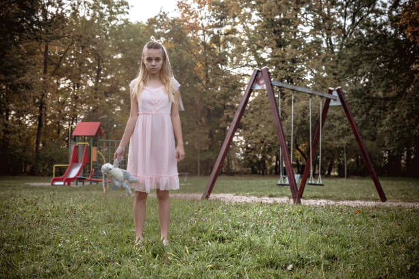 Little girl plays with her doll in a stroller - outdoors portrait