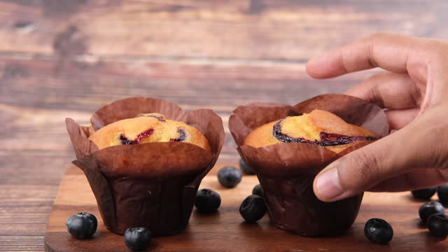 hand pick blueberry muffins on table