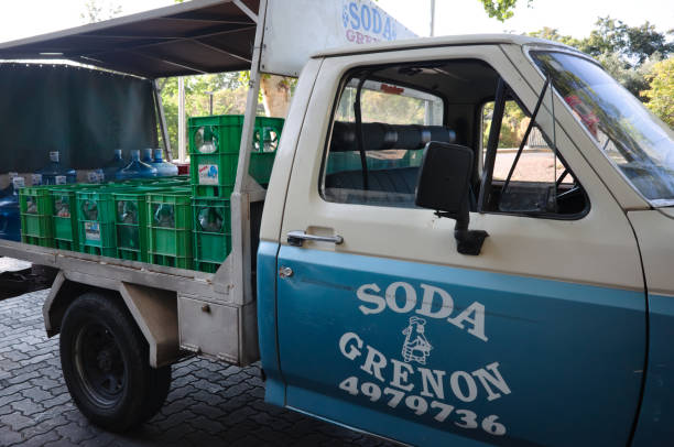 Mendoza, Argentina - January, 2020: Truck delivers bottled water. Open trailer truck unloads drinking water in large bottles and green boxes with soda water. Truck of Soda Grenon water company