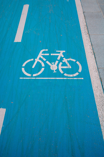 Bike road sign on the blue background. Bicycle lane on the pavement. Healthy lifestyle.