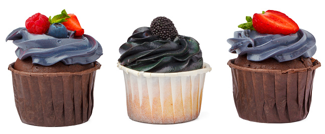 Close up color image depicting a selection of freshly baked delicious cakes and cupcakes displayed in a row at a food market. Selective focus on one of the cupcakes while the others are defocused in the background. Room for copy space.