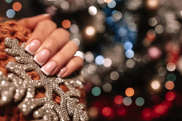 istock Female hand holding a silver snowflake against the Christmas tree bokeh lights. 1347292053