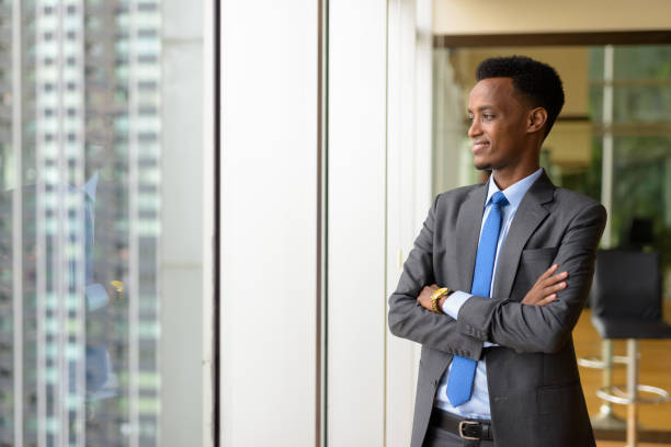 istock Portrait of handsome African businessman looking through window while thinking 1347292075
