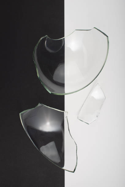 istock Broken glass pieces on black and white background. Close up, top view. 1347292606