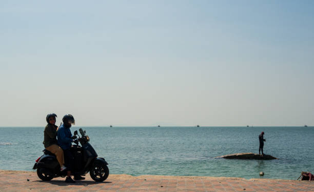 landscape viewpoint for design postcard and calendar front view sea sky and clouds on  holiday has motorbike. Scooter running And Asian man stands fishing on small rock