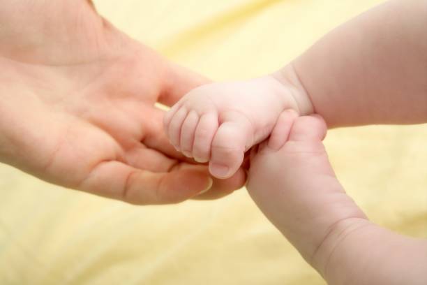 istock baby feet in mother hands playing 1347295584