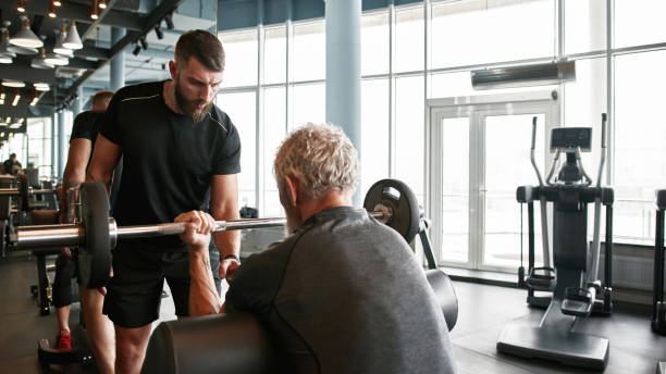 istock Professional trainer with concentrated face expression assisting senior powerlifter 1347296964