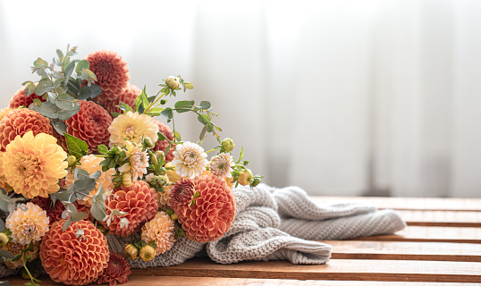A bouquet of yellow and orange chrysanthemums and a knitted element on a blurred background, copy space.