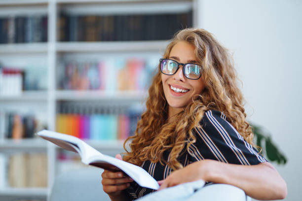 istock Young woman sitting  with a book, laptok in the library and taking learning notes. 1347297427