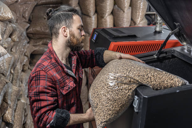The man loads the pellets in the solid fuel boiler, working with biofuels. The man loads the pellets in the solid fuel boiler, working with biofuels, economical heating. granule stock pictures, royalty-free photos & images