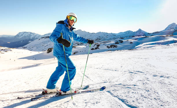 Expert skier on blue uniform on relax moment at french alps ski resort - Winter adventure and sport concept with professional guy on mountain top ready to ride down - Bright vivid azure filter Expert skier on blue uniform on relax moment at french alps ski resort - Winter adventure and sport concept with professional guy on mountain top ready to ride down - Bright vivid azure filter ski instructor stock pictures, royalty-free photos & images