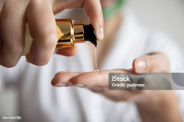 A Woman Presses On The Dispenser Of Beauty Care Products Blurred Background Stock Photo - Download Image Now