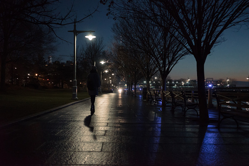Back view of a woman walking along seafront at night