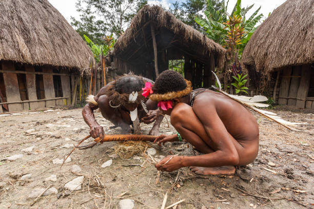 Men of the Dani tribe in a traditional dress kindling fire. Indonesian New Guinea Wamena, Indonesia - January 9, 2010: Men of the Dani tribe in a traditional dress kindling fire. Baliem Valley Papua, Irian Jaya, Indonesian New Guinea dani stock pictures, royalty-free photos & images