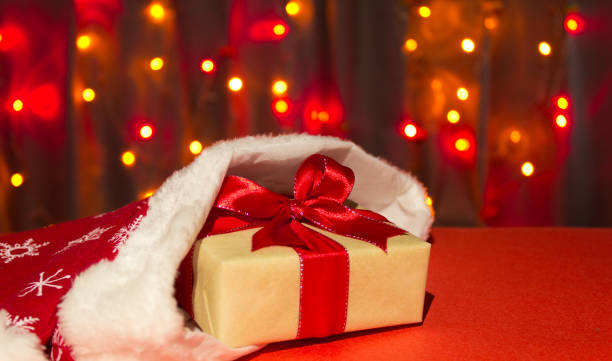 istock Christmas present box  in christmas hat on a background of multicolored bokeh 1347302817