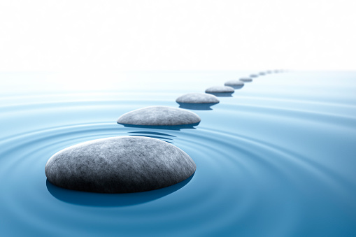 Row of gray pebble stones in blue water ripples with reflection - zen and nature concept