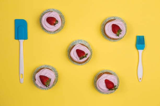 istock Cupcake decorated with pink cream and a strawberry on yellow background 1347304630
