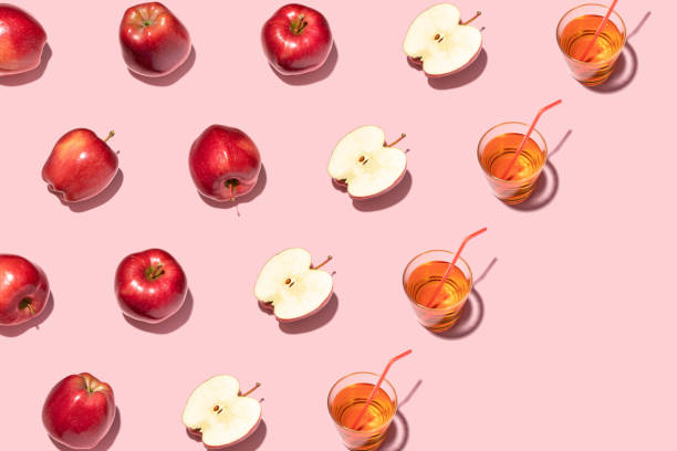 istock Red apples and juice on pink background. Pattern, top view, flat lay. 1347304654