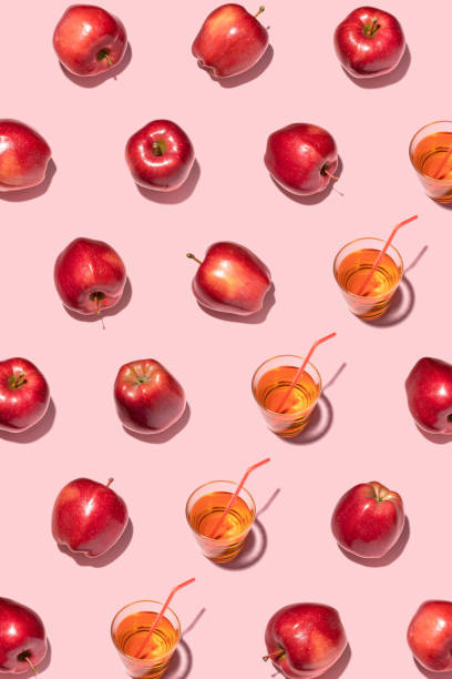 istock Red apples and juice on pink background. Pattern, top view, flat lay. 1347304715