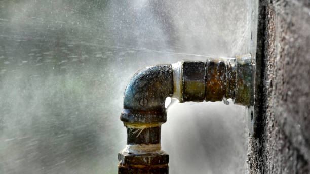 Old rusty pipe with leak and water spraying out under pressure leaky leaking