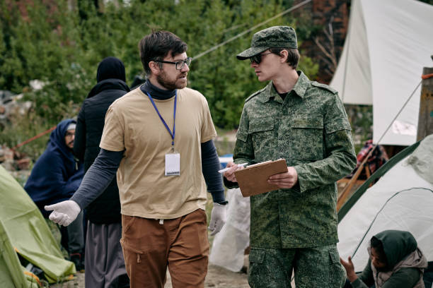 istock Male volunteer and young man in green uniform discussing working points 1347306118