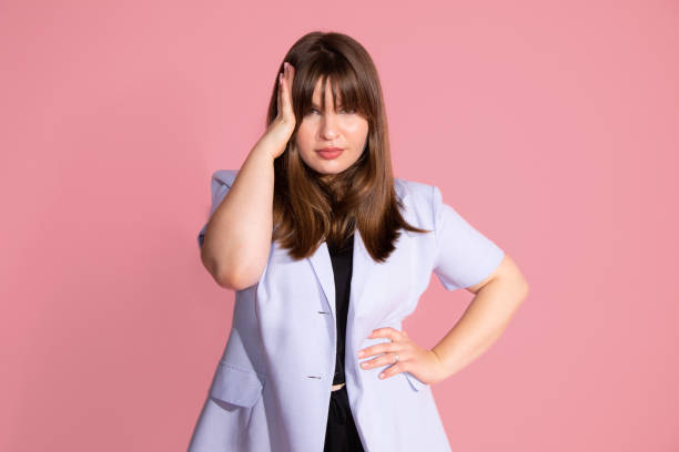 istock Young woman thinking, looking tired and bored with depression problems with arm near heard , studio shot, pink background 1347306174