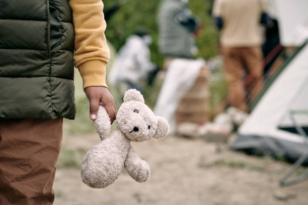 Hand of homeless child holding white teddybear stock photo